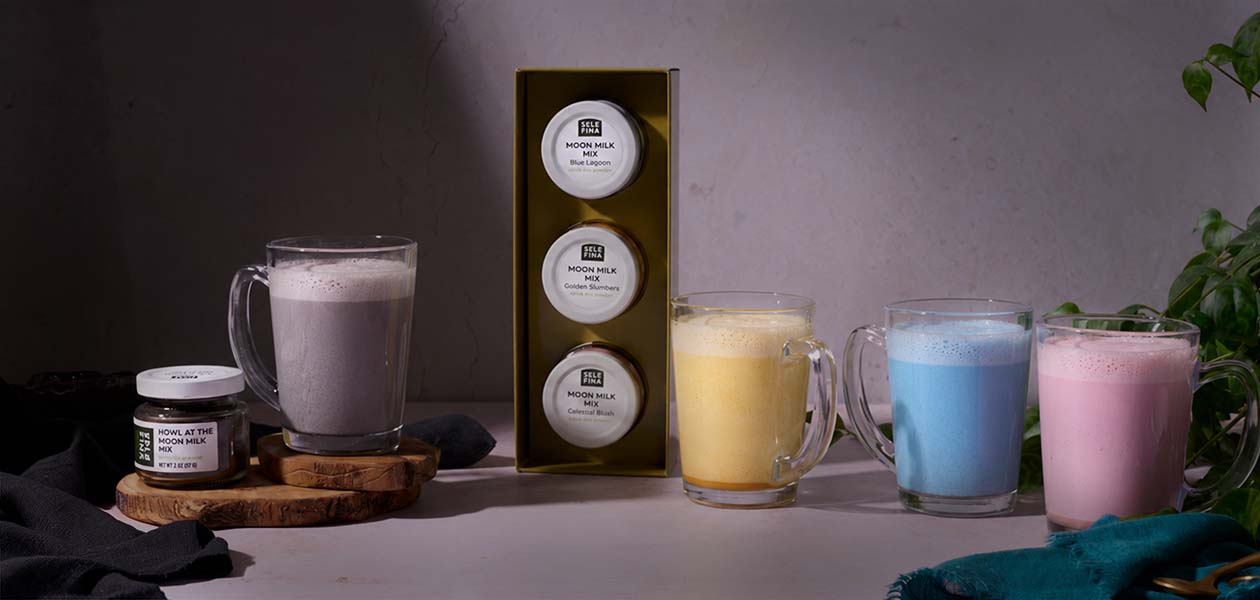 All four moon milks in a row, Howl at the Moon beside the Three Sheep gift box with Golden Slumbers, Blue Lagoon, and Celestial Blush
